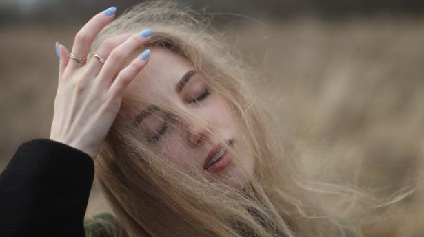 Person stretching gently near a large window with natural light.