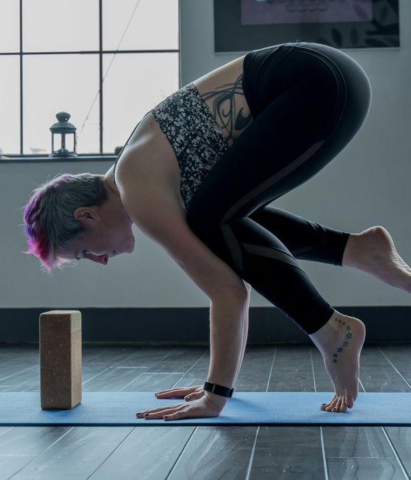 Woman in a focused yoga pose in a spacious studio.
